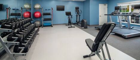 A gym with exercise equipment, a treadmill, and a bench.