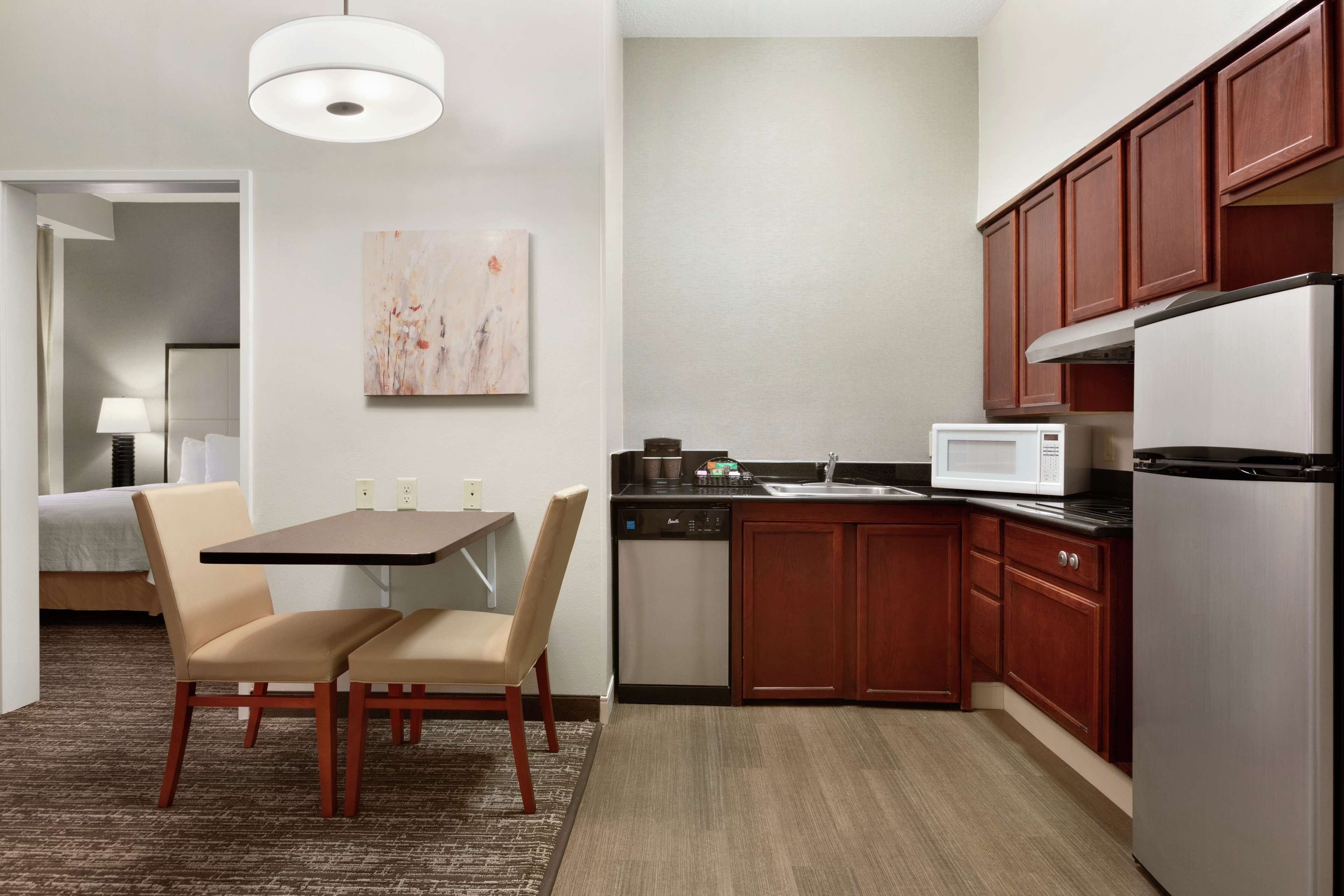 A compact hotel room with a dining area, kitchenette, and a bed.
