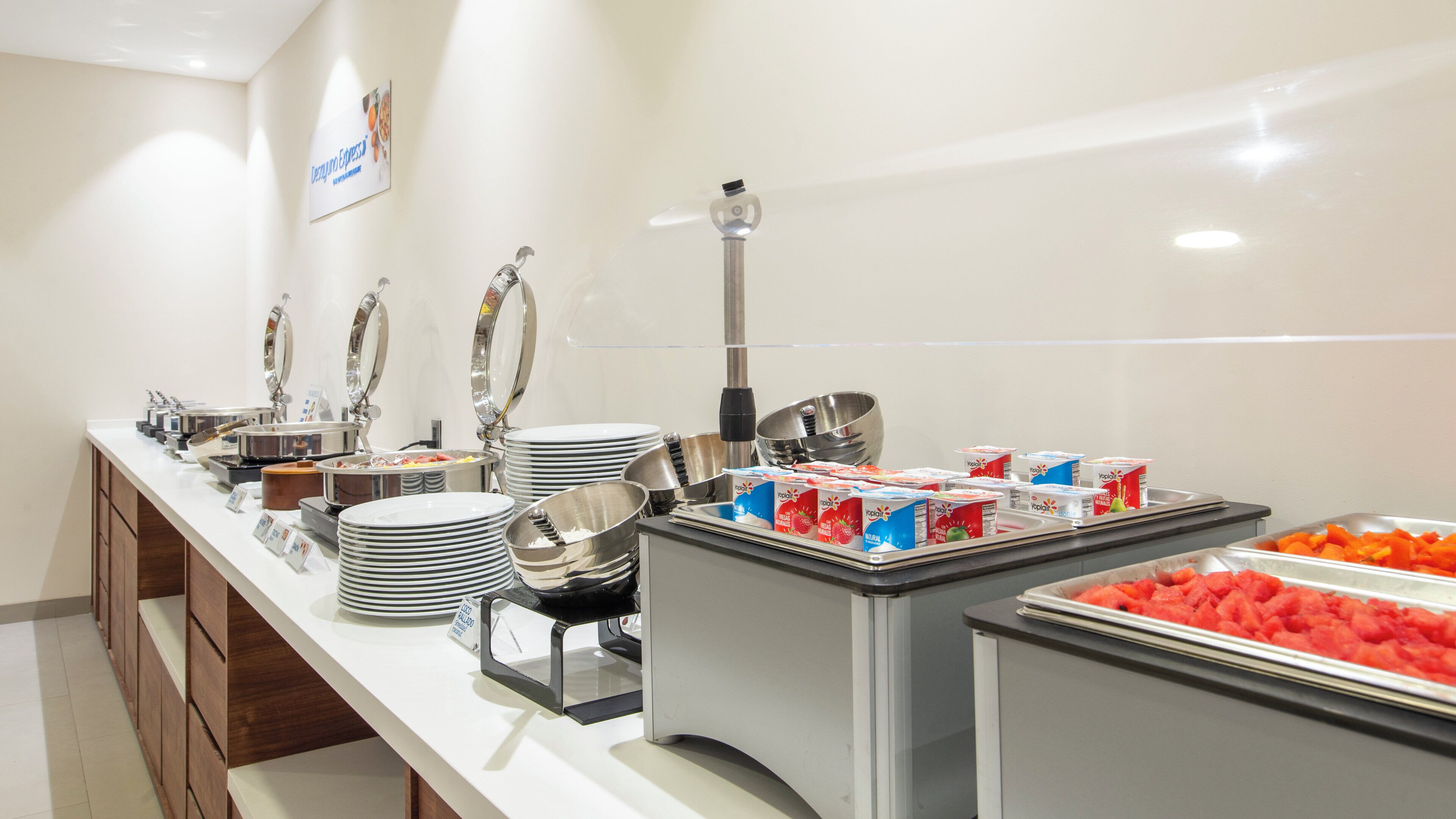 A buffet setup with various food items, including yogurt and fruit.