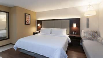 Una habitación de hotel con una cama grande, mesitas de noche, una lámpara y un cuadro en la pared.