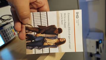 A hand holding a business card with a photo of three people and text in Spanish.
