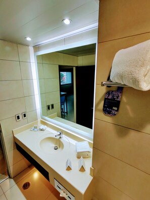 A hotel bathroom with a large mirror, a sink, and a towel rack.