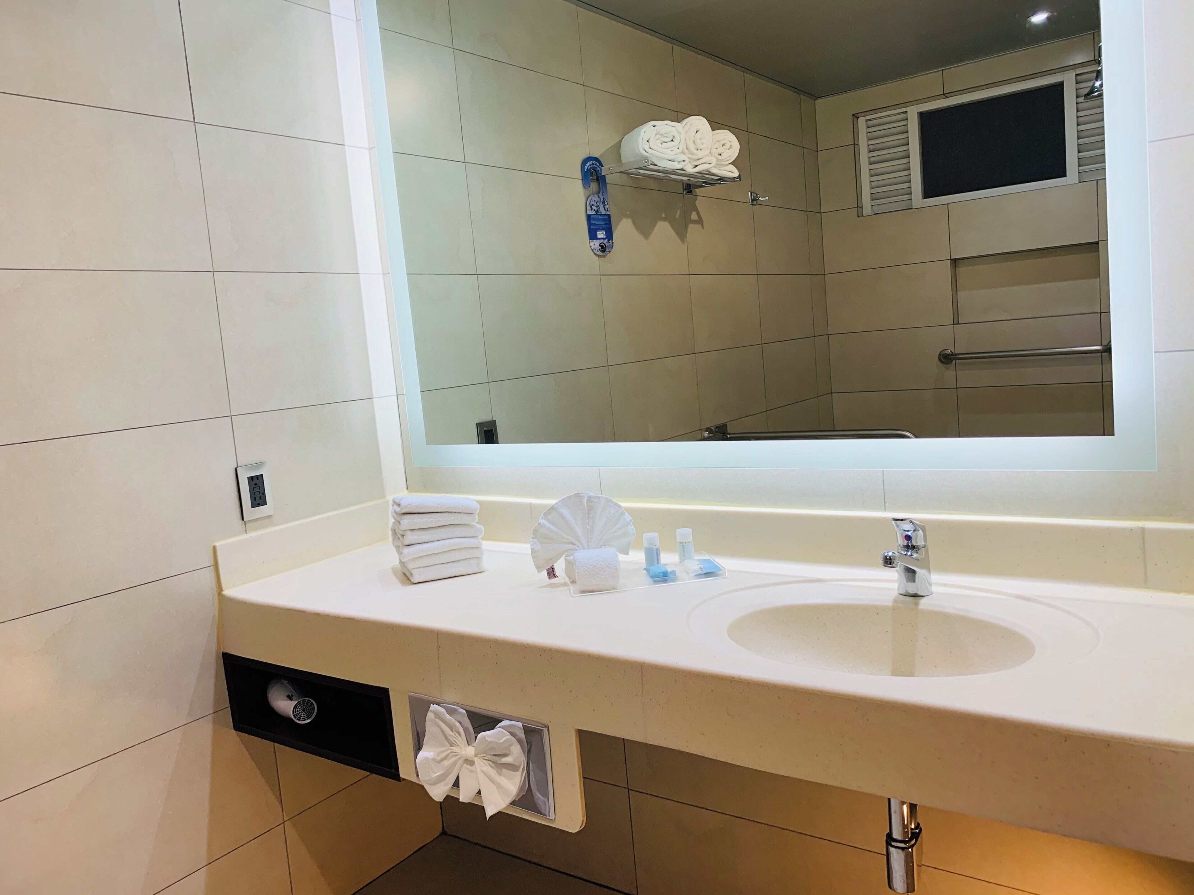 Een hotelbadkamer met een grote spiegel, een wastafel en een handdoekhouder.
