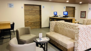 Un vestíbulo de hotel con una recepción, dos monitores de computadora, un sofá y una pequeña mesa con un menú.