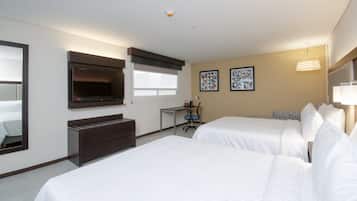 A hotel room with two beds, a desk, a dresser, a TV, and two framed pictures on the wall.