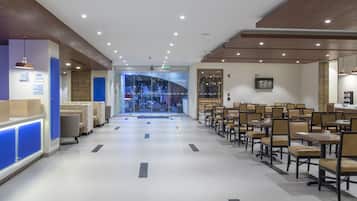 Un hall d’hôtel comprenant un comptoir d’accueil, un espace salon et une vue sur la rue.