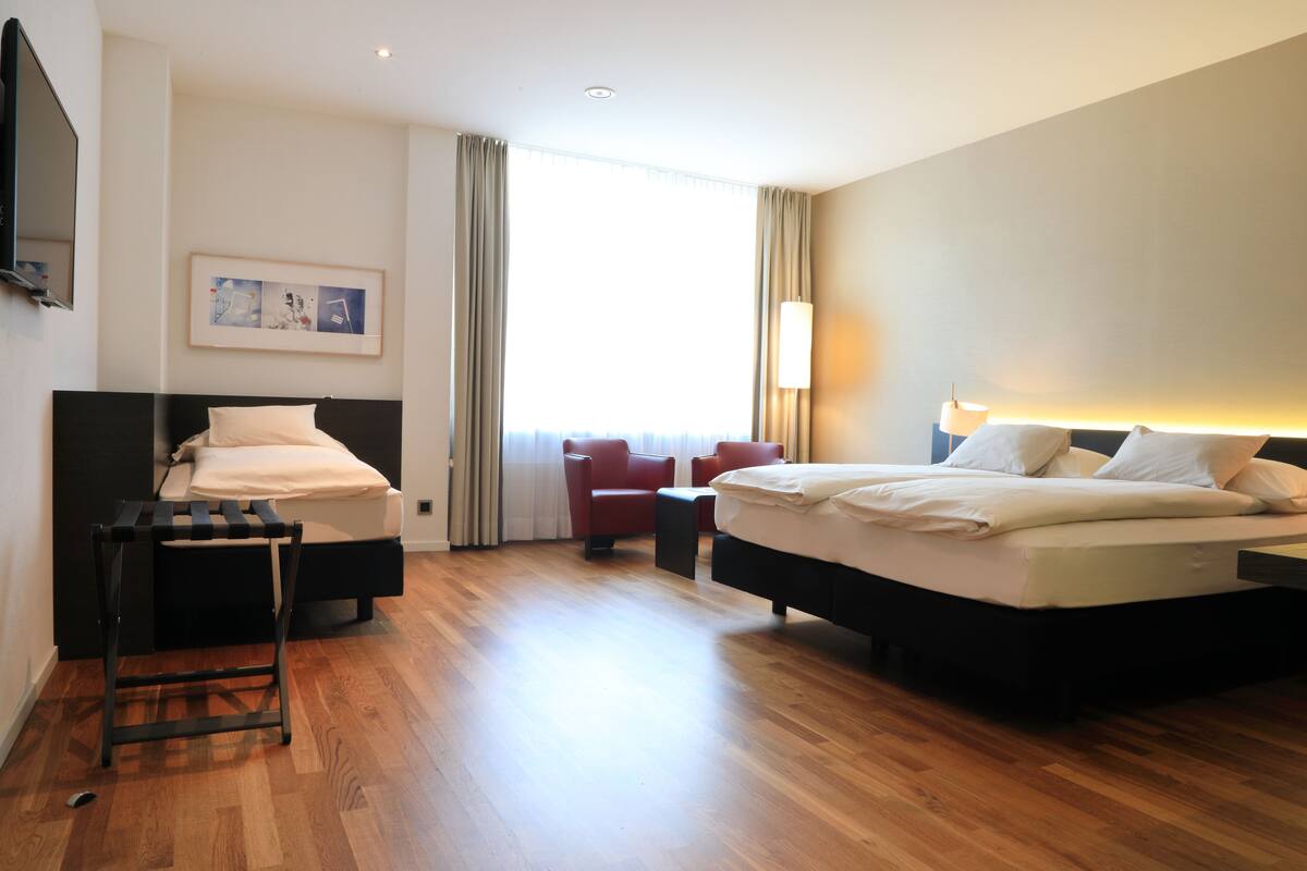 Ein Hotelzimmer mit einem großen Bett, einem Schreibtisch, einem Stuhl und einem Fernseher.