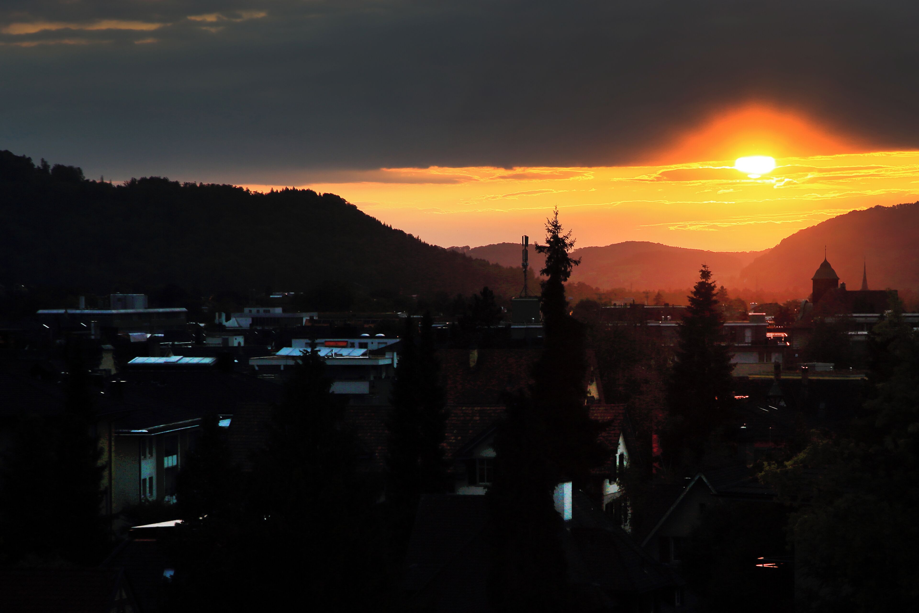 A town at sunset with buildings silhouetted against the sky.