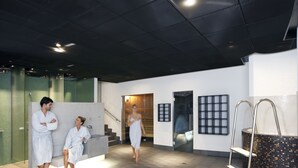A modern spa area with a large bathtub, a glass wall, and a staircase leading to another level. - Hotel Banana City Winterthur (Winterthur)