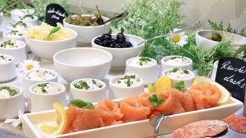 Une variété de plats de fruits de mer, notamment du saumon et des olives, servis dans de petits bols et dans un plat rectangulaire, avec une pancarte indiquant « plats à la panzanese ».