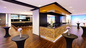 A modern hotel lobby with a reception desk, seating area, and a stage for presentations. - Hotel Banana City Winterthur (Winterthur)