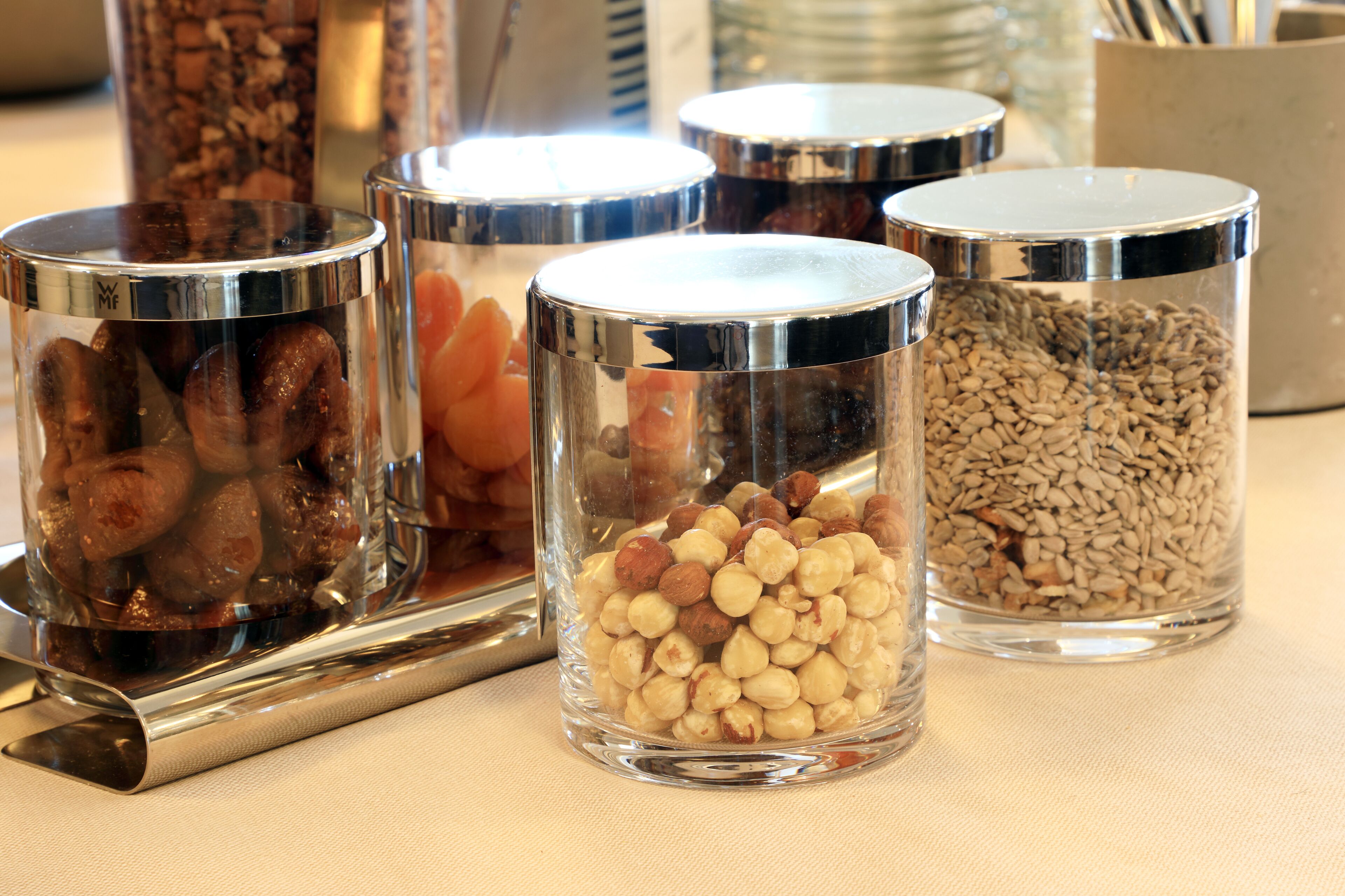 Four glass containers with metal lids on a table.