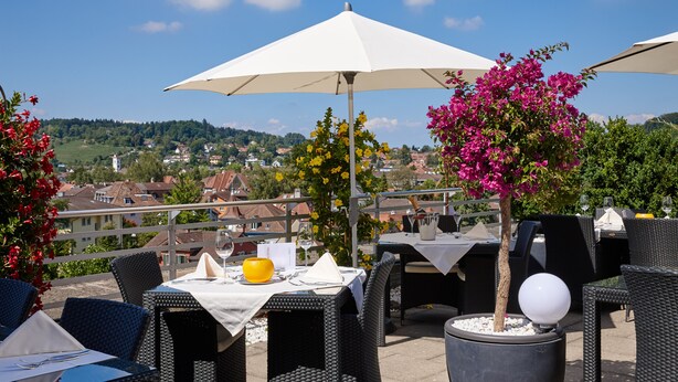 An outdoor dining area with tables, chairs, and umbrellas. - Hotel Banana City Winterthur (Winterthur)