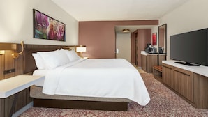 Een hotelkamer met een groot bed, een flatscreen televisie, een bureau en een koffiezetapparaat.