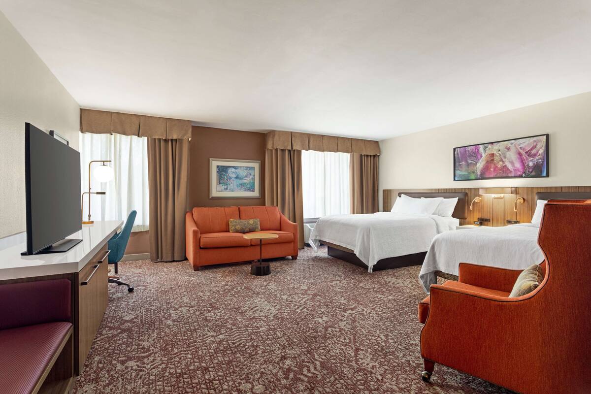 Una habitación de hotel con televisión, sofá, cama y escritorio.