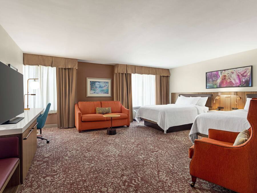 Una habitación de hotel con televisión, sofá, cama y escritorio.