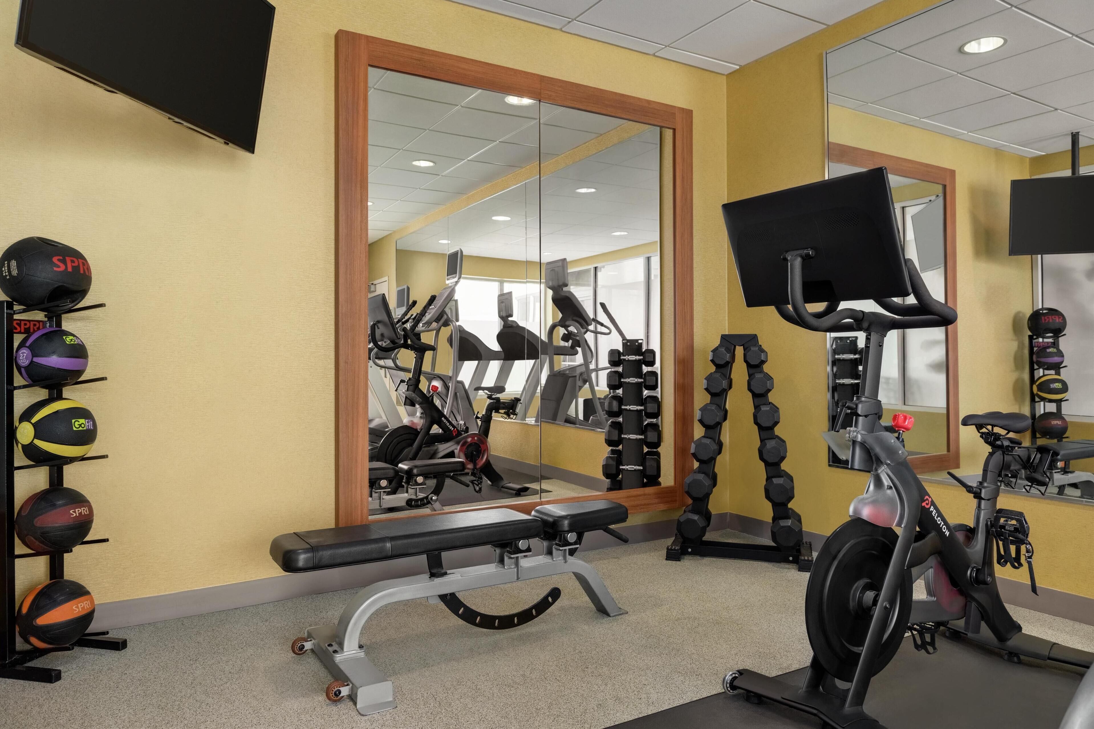 A gym with exercise equipment, a bench, and a mirrored wall.