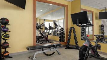 A gym with exercise equipment, a bench, and a mirrored wall.