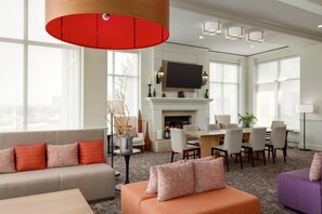 A spacious living room with a fireplace, a dining area, and a large window providing natural light. - Hilton Garden Inn Allentown Bethlehem Airport (Allentown)