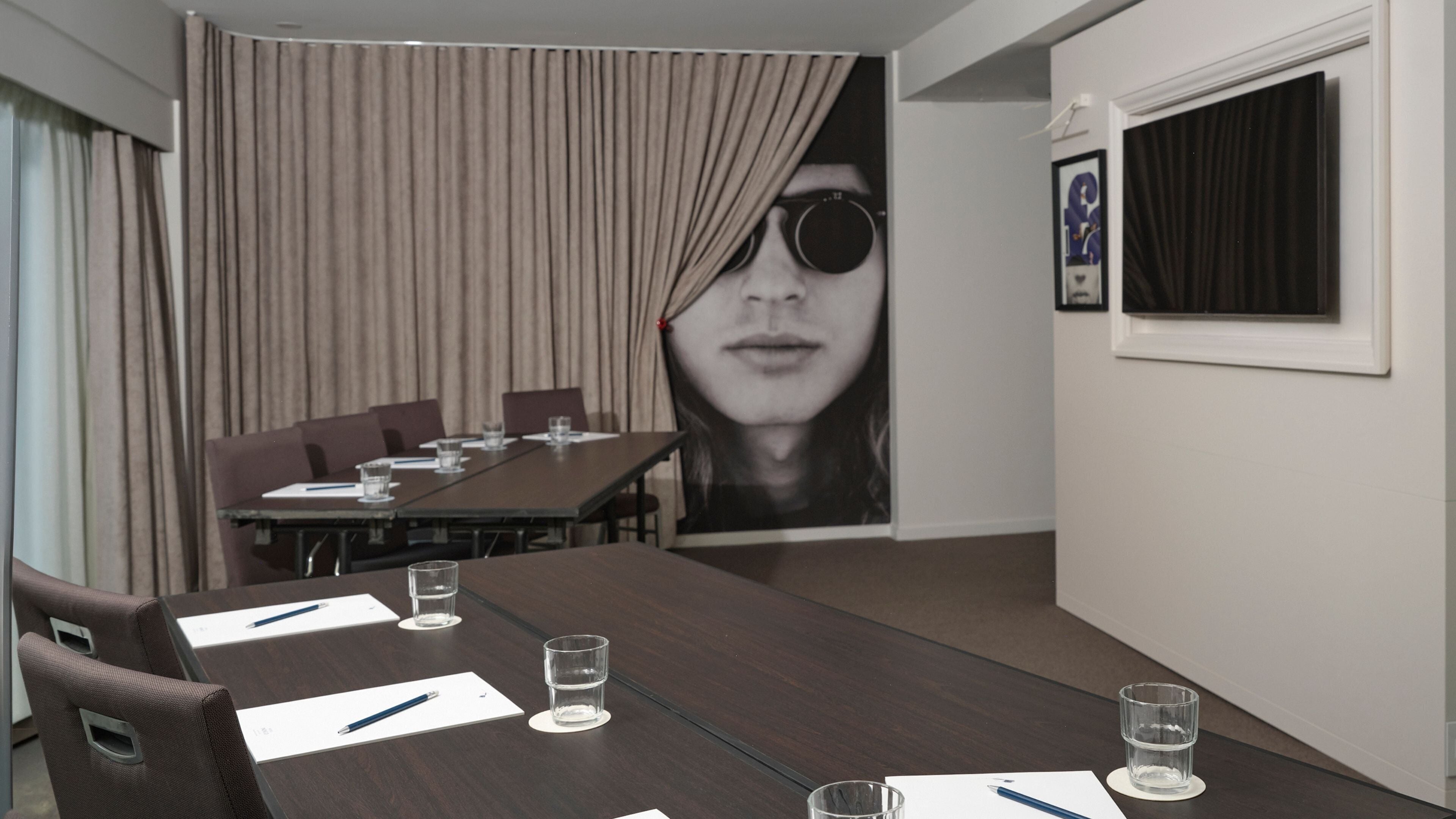 Ein Konferenzraum mit einem langen Tisch, Stühlen und einem großen Plakat an der Wand.