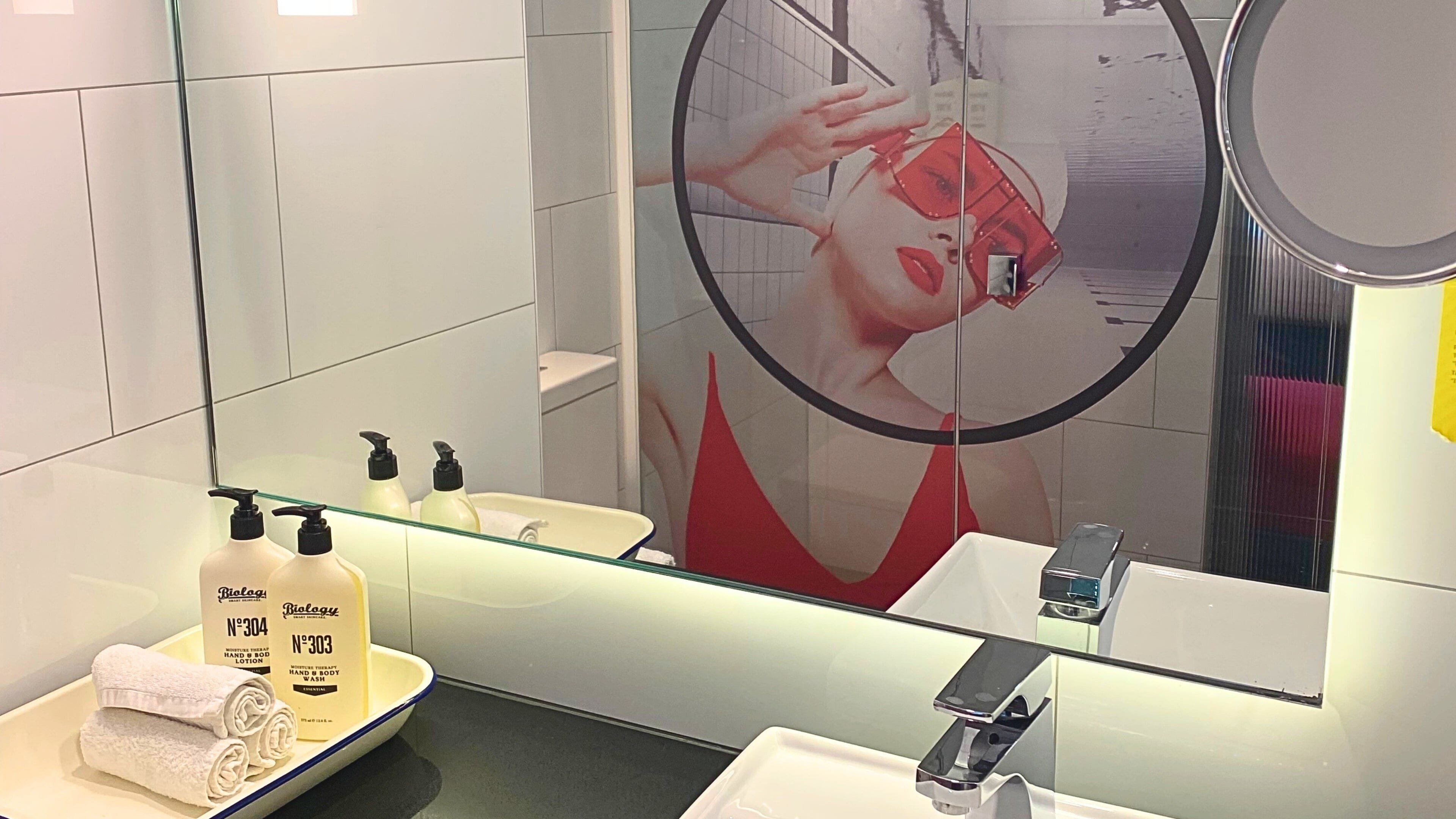A bathroom with a large mirror, a sink, and two bottles of lotion.