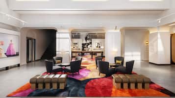 A modern lobby with a central seating area, a staircase, and a large artwork on the wall.