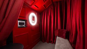 A red theater room with a circular mirror, a DNP machine, and a bench.