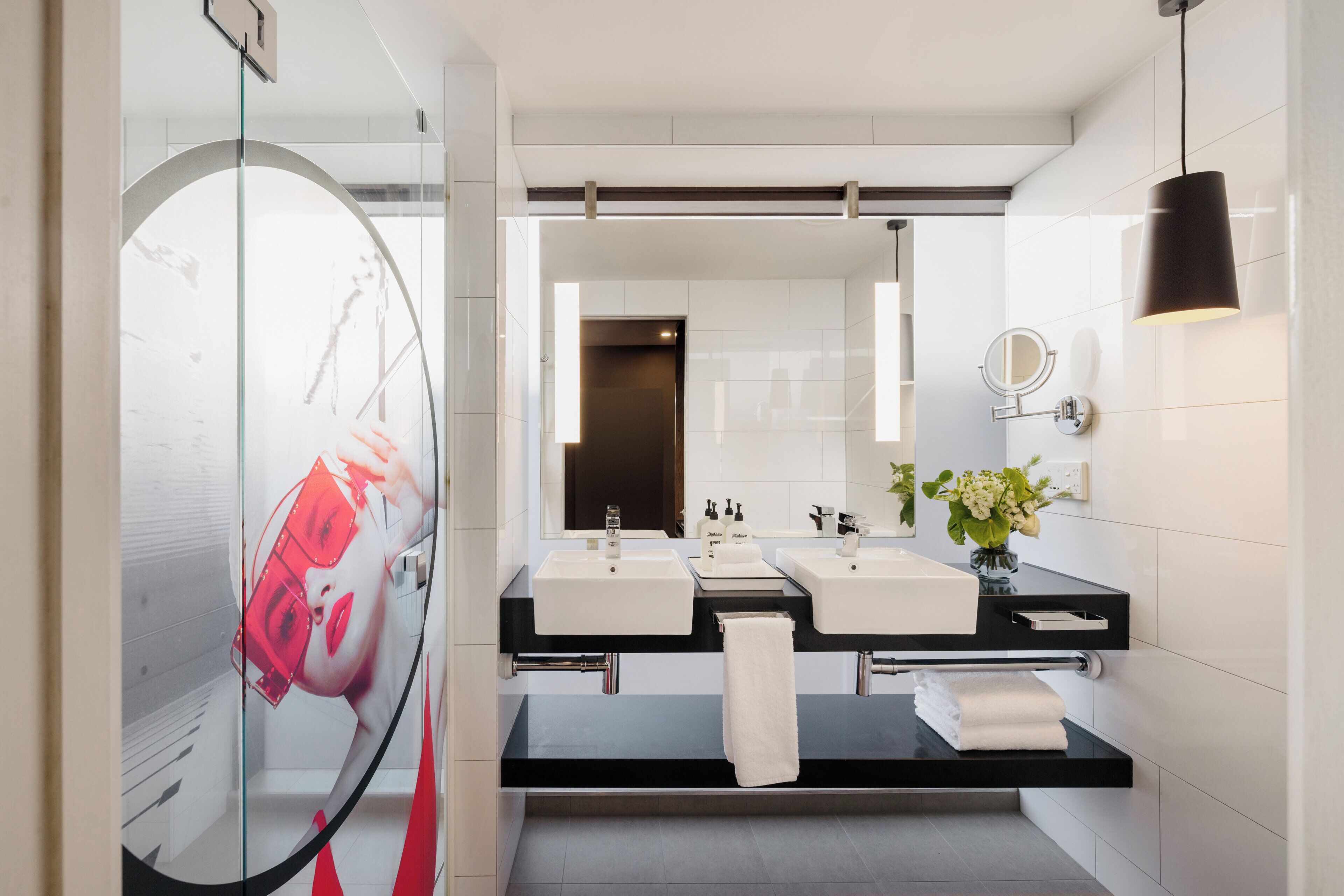 A modern bathroom with two sinks, a large mirror, and a glass shower enclosure.