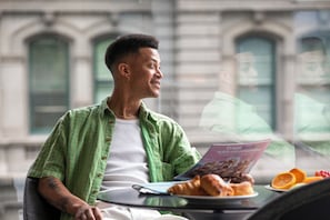 A person sitting at a table with a laptop, a magazine, and a croissant. - Hotel Indigo Melbourne on Flinders by IHG (Melbourne)