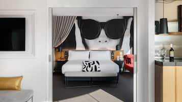 A modern hotel room with a large bed, a desk, and a red sofa.