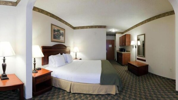 A hotel room with a bed, bedside tables, a lamp, a painting on the wall, and a kitchenette area. - Holiday Inn Express Hotel & Suites Laurinburg by IHG (Laurinburg)