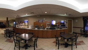 A hotel lobby with a central counter, seating area, and a clock on the wall.