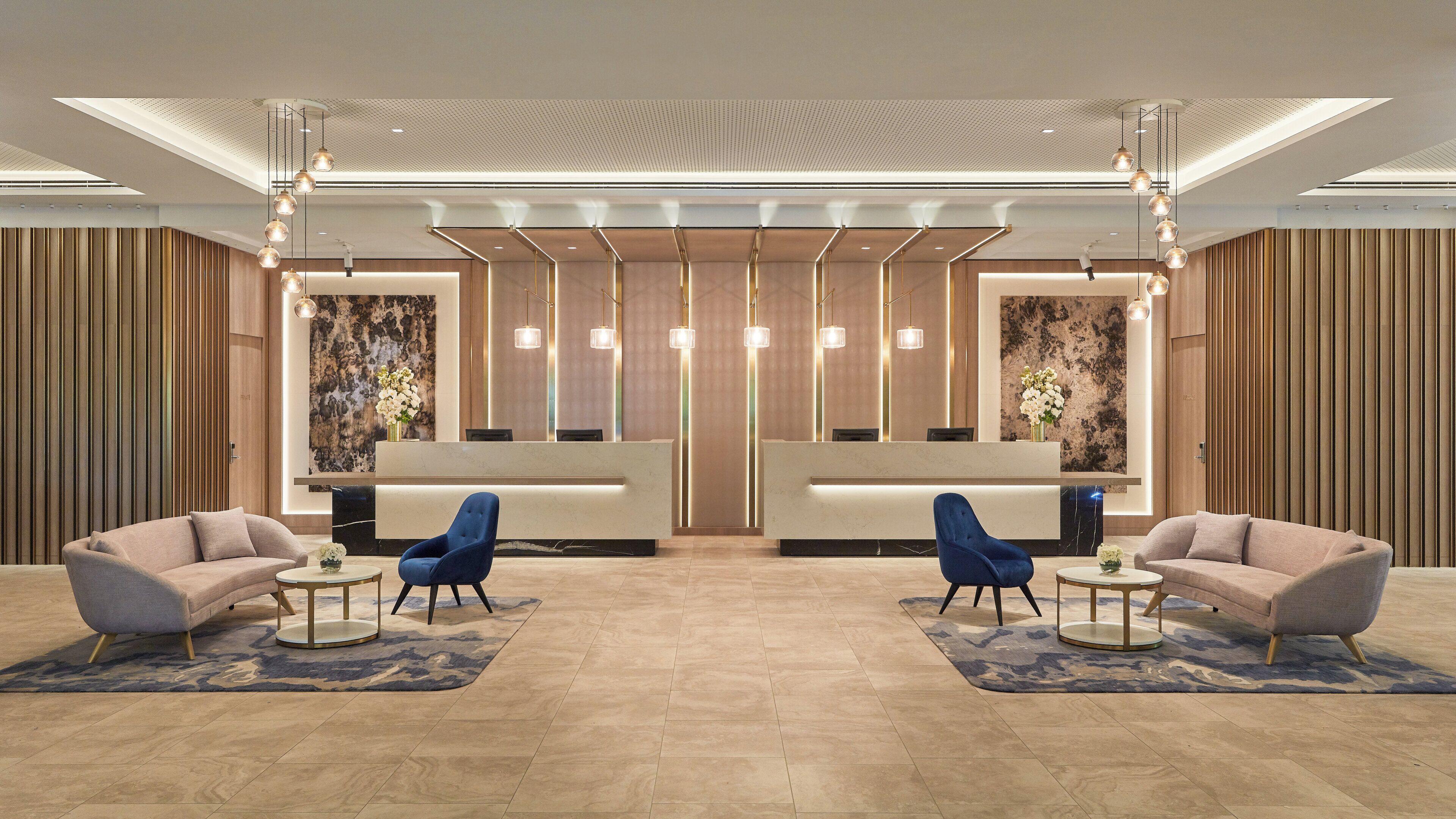 A hotel lobby with a reception desk, two sofas, and a blue chair.