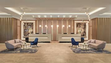 A hotel lobby with a reception desk, two sofas, and a blue chair.