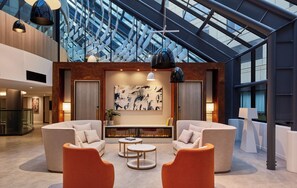 A modern interior with a high ceiling, two sofas, a coffee table, and a fireplace. - Crowne Plaza Melbourne by IHG (Docklands)
