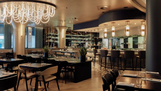 A modern restaurant with a bar area, wooden tables, and chairs. - Crowne Plaza Melbourne by IHG (Docklands)