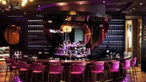 A bar area with a circular bar counter, multiple bar stools, and a variety of bottles and glasses on shelves. - Crowne Plaza Melbourne by IHG (Docklands)