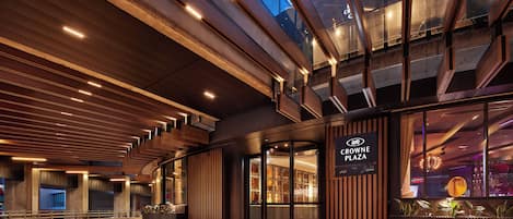 A modern building entrance with a glass facade, wooden paneling, and a sign for Crowne Plaza.