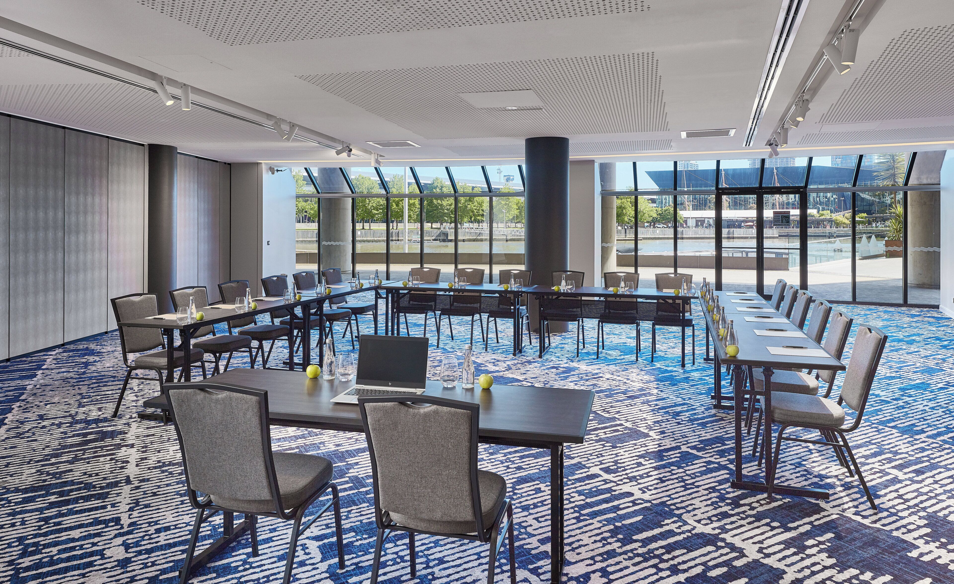 A conference room with a long table, chairs, and a carpeted floor.