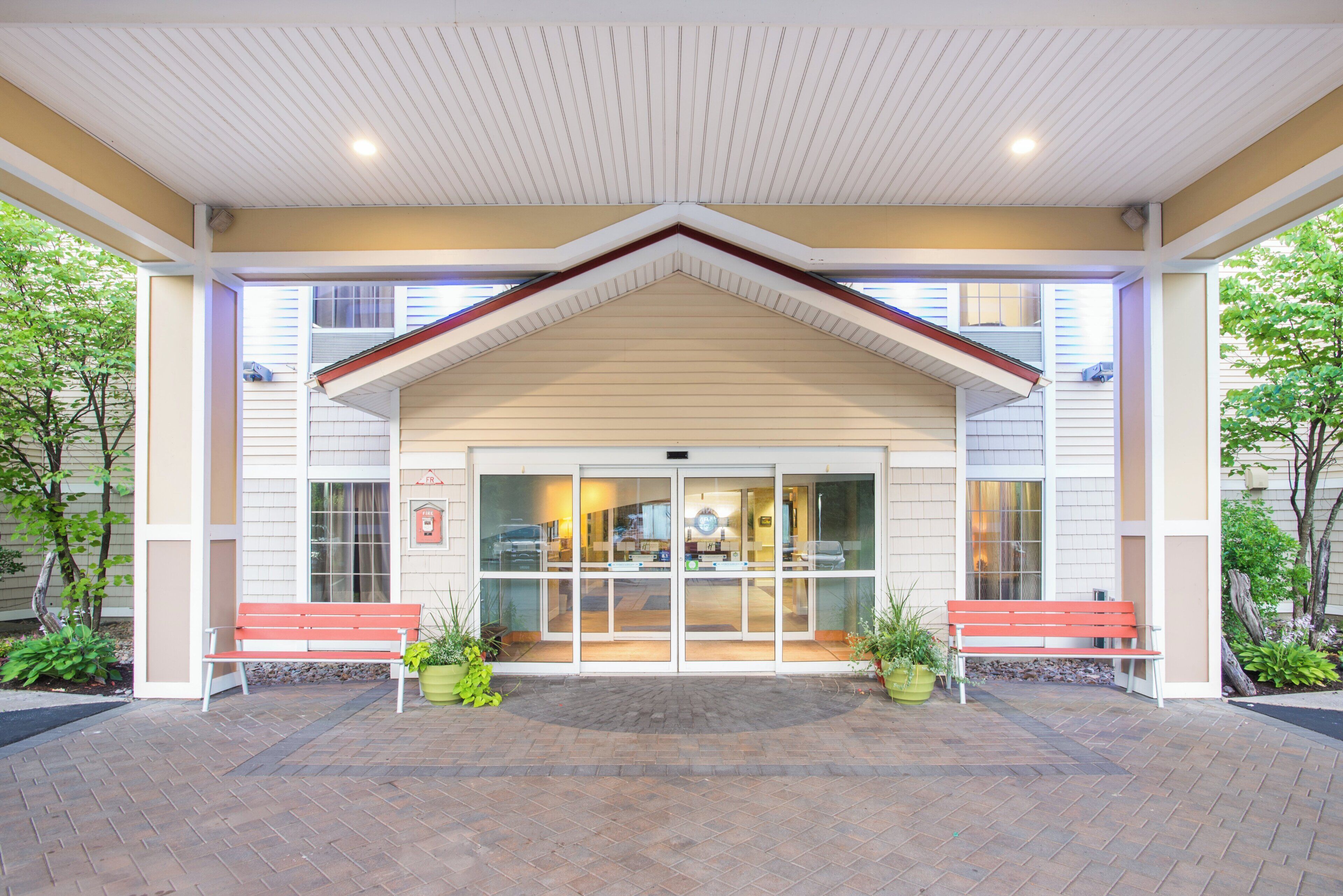 A building with a covered entrance, two benches, and a fire alarm sign.