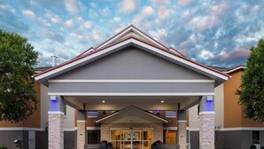 Entrada de hotel com design moderno, destacando um toldo imponente e pilares de pedra.