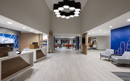 A spacious lobby with a reception desk, seating area, and a modern ceiling light fixture.