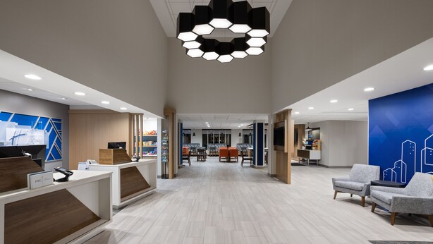 Um hall amplo com balcão de recepção, área de estar e luminária moderna no teto.