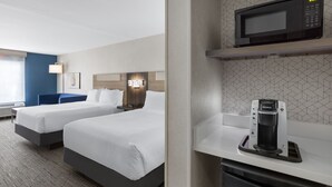 Quarto de hotel com duas camas, micro-ondas, máquina de café e uma pequena cozinha.