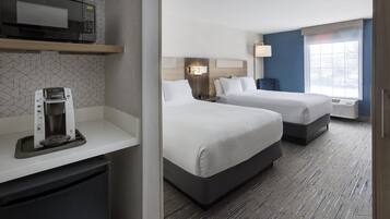A hotel room with two beds, a microwave, a coffee maker, and a window with a view.