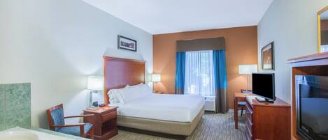 A hotel room with a large bed, a TV, a desk, a chair, a bathroom with a bathtub, and a window with curtains.