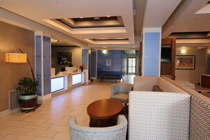 A hotel lobby with a reception desk, seating area, and a view of the hallway.