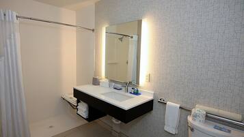A modern bathroom with a double sink vanity, a shower, and a toilet.
