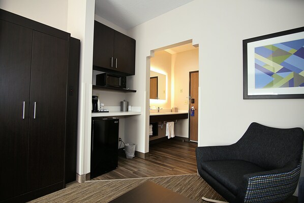 A modern hotel room with a dark wood wardrobe, a black refrigerator, a microwave, a sink, and a chair. - Holiday Inn Express & Suites Ashland by IHG (Ashland)