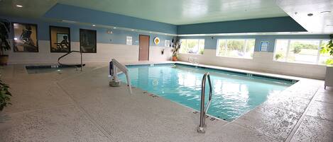 Una piscina interior con agua cristalina, un trampolín y una silla para salvavidas.